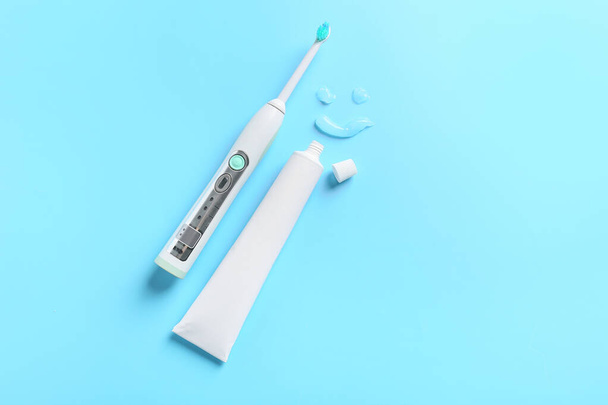 Elektrische tandenborstel en plak op kleur achtergrond - Foto, afbeelding