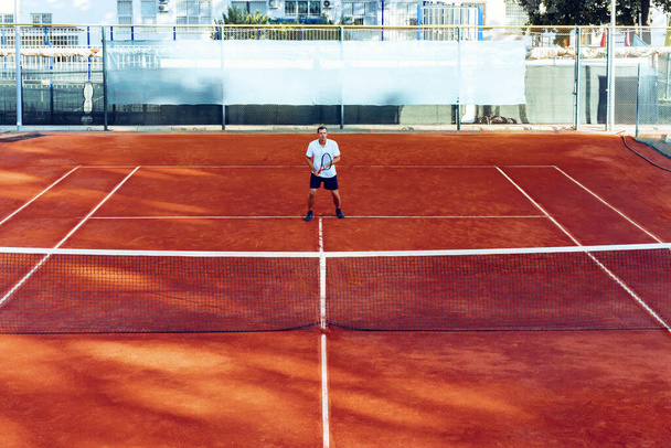 Man plays tennis on clay tennis field view from afar - Foto, imagen