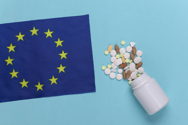 Europese vlag en een fles pillen op een blauwe achtergrond. Bovenaanzicht - Foto, afbeelding