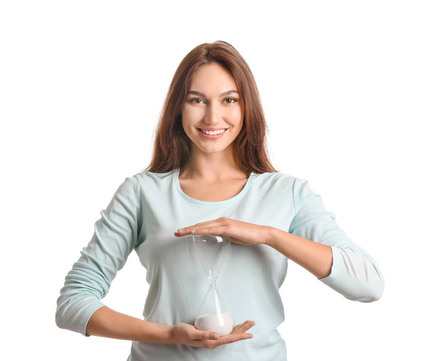 Young woman with hourglass on white background - Zdjęcie, obraz
