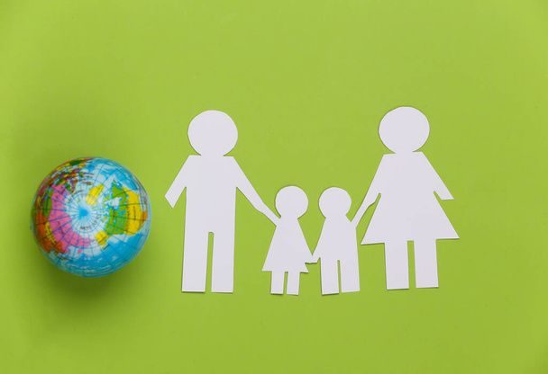 Familia de papel junto con globo sobre fondo verde. Concepto de ecología, población, familia, día de la tierra. Mundo nuestra casa - Foto, Imagen