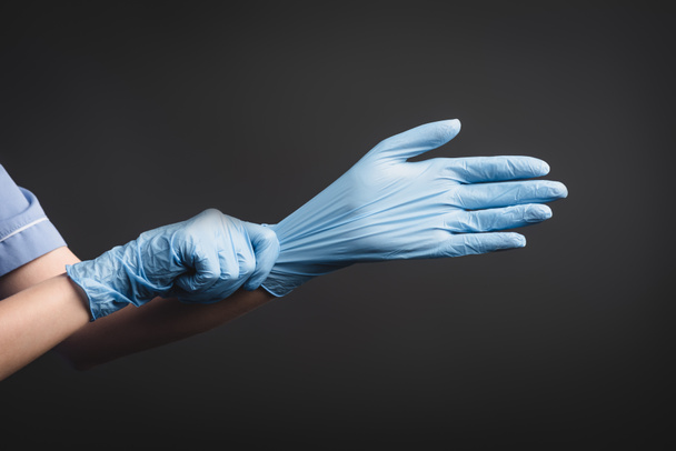 vista recortada de la enfermera con guantes de látex aislados en gris oscuro - Foto, Imagen
