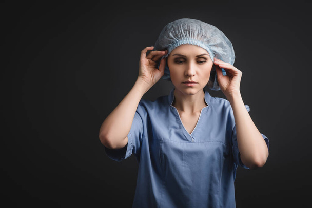 enfermera con gorra médica azul aislada en gris oscuro - Foto, Imagen