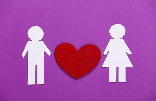 Любовний концепт. Паперовий чоловік і жінка з червоним серцем на фіолетовому тлі
. - Фото, зображення