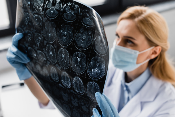 rentgen w rękach naukowca w masce medycznej i rękawicach lateksowych na rozmytym tle - Zdjęcie, obraz
