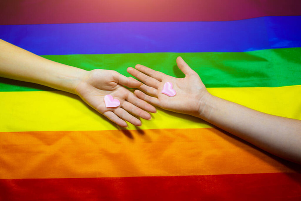 Lgbt topluluğunun renkli bayrağı. Gökkuşağı arka planında iki kadın eli. Lezbiyen ve gey sorunları. Evliliğin homoseksüel yönelimli çiftler için yasallaştırılması. Cinsiyet eşitliği. - Fotoğraf, Görsel