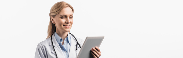 happy nurse in white coat using digital tablet isolated on white, banner - Fotografie, Obrázek