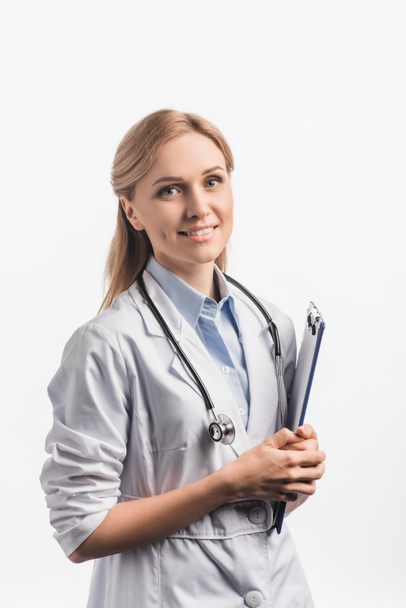 infirmière heureuse en manteau blanc tenant presse-papiers isolé sur blanc - Photo, image