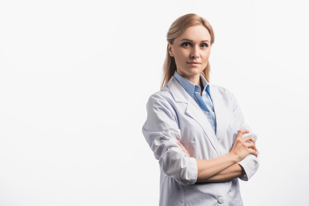 confident nurse in white coat standing with crossed arms isolated on white - Foto, Imagen