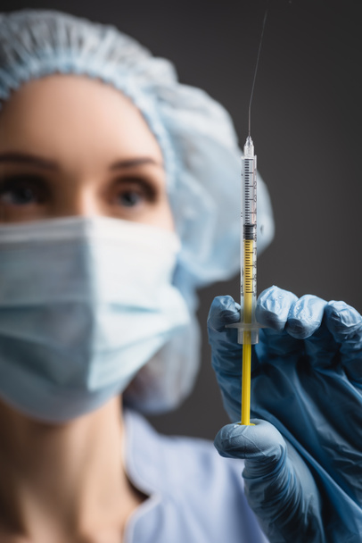 syringe with vaccine splash in hand of nurse in latex glove on blurred background isolated on dark grey - Fotoğraf, Görsel