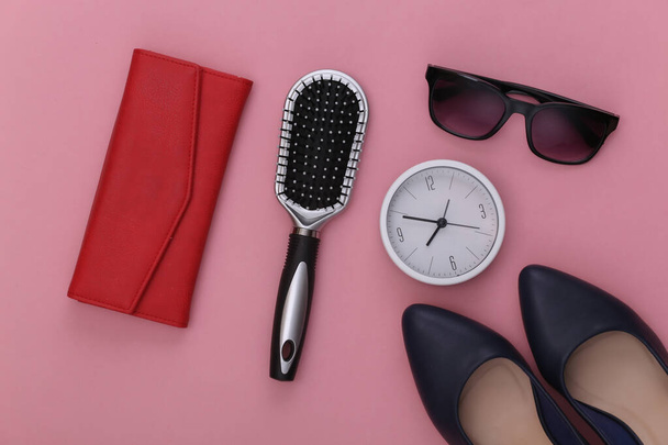 Accessoires für Frauen. Hochhackige Schuhe, Geldbörse, Kamm, Sonnenbrille und Uhr auf rosa Hintergrund. Ansicht von oben. - Foto, Bild