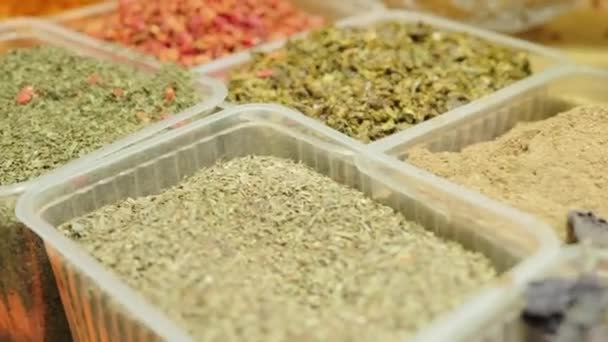 Äärimmäinen lähikuva ja erilaisten mausteiden ja kuivien yrttien kädessä pidettävä seuranta muovisissa elintarvikepakkauksissa markkinoilla - Materiaali, video