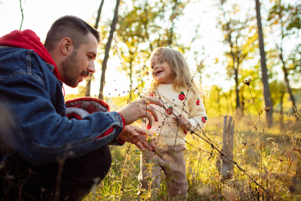 Happy father and little cute daughter walking down the forest path in autumn sunny day - Foto, Imagem