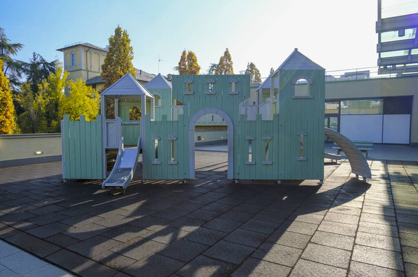 Детская игровая площадка в форме замка через городской пейзаж и голубое небо. Детская площадка на открытом воздухе - Фото, изображение