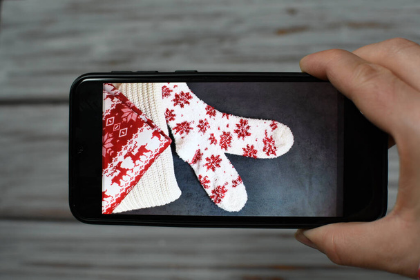 Neujahrsbild am Telefon. Socken, Pullover im Bildschirmschoner. Weibliche Hand hält ein Gadget - Foto, Bild