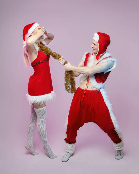 guy and girl in Santa Claus costumes. photo session in the Studio. Christmas and New year concept - Foto, immagini
