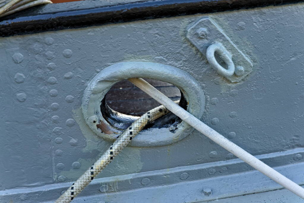 Lignes d'amarrage partant d'un trou de taquet sur un navire en acier blanc au port.  - Photo, image