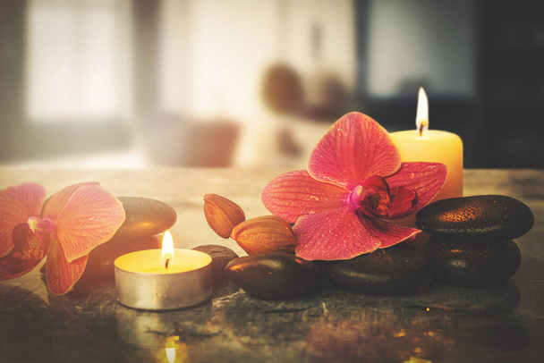Schönheitsbehandlung und Wellness Hintergrund mit Massagesteinen Orchideenblumen und brennenden Kerzen im Kurzentrum - Foto, Bild