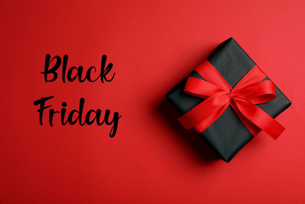 Phrase Black Friday and gift box on red background, top view - Foto, imagen