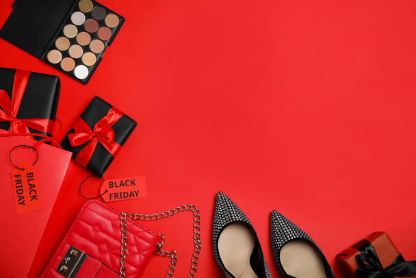 Gift boxes, cosmetics, shoes, stylish women's accessories and space for text on red background, flat lay. Black Friday sale - 写真・画像