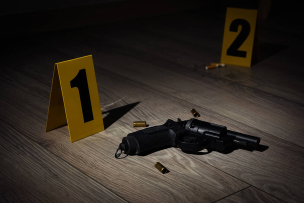 Gun and shell casings on wooden floor at crime scene - Fotoğraf, Görsel