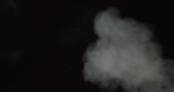 Atmosphärischer Rauch VFX Overlay-Element. Dunkler Hintergrund. Rauch in Zeitlupe auf schwarzem Hintergrund. Vor schwarzem Hintergrund schwebt weißer Rauch langsam durch den Raum. Nebelwirkung. Nebeleffekt. - Foto, Bild