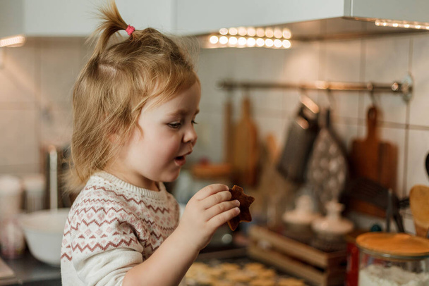 Το κοριτσάκι ψήνει μπισκότα με τη μορφή αστεριών. Χριστουγεννιάτικα μπισκότα. - Φωτογραφία, εικόνα
