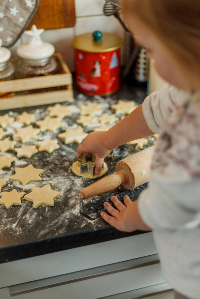 little girl bakes cookies in the form of stars. Christmas cookies. - Фото, изображение