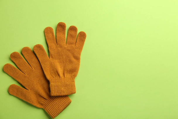 Pair of stylish woolen gloves on green background, flat lay. Space for text - Foto, imagen