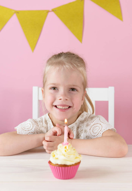Happy girl with cupcake on a pink background. - Foto, imagen