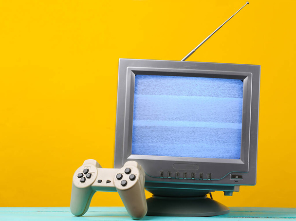 Antenne ouderwetse retro tv ontvanger met gamepad op gele achtergrond. Retro-entertainment jaren '80 - Foto, afbeelding
