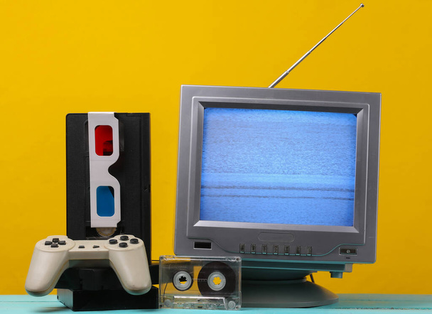 Retro media, rozrywka lat 80-tych. Antena staromodny odbiornik telewizyjny retro, okulary stereo anaglif, kaseta audio i wideo, gamepad na żółtym tle.  - Zdjęcie, obraz