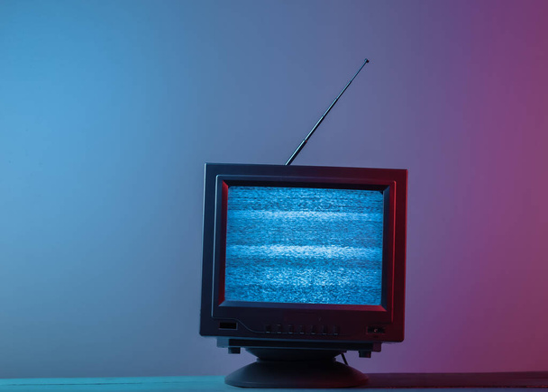 Mini ricevitore antenna tv retrò. Un televisore vecchio stile. Luce al neon sfumata blu rosa. Rumori televisivi, nessun segnale. Onda retrò anni 80 - Foto, immagini