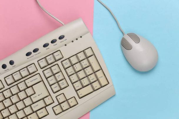Старомодная ретро-клавиатура и компьютерная мышь на сине-розовом пастельном фоне. Ретро компьютер. Вид сверху - Фото, изображение