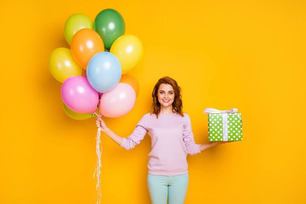 Portrait of cheerful woman hold helium baloons green dotted gift box she prepare for friends anniversary wear casual style pullover isolated over shine color background - Foto, Imagem