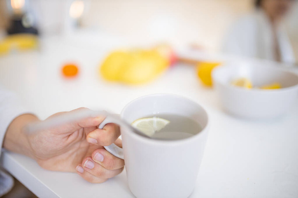 Hand hält eine Tasse Zitronentee mit einem Strohhalm und Zitronenscheibe - Foto, Bild