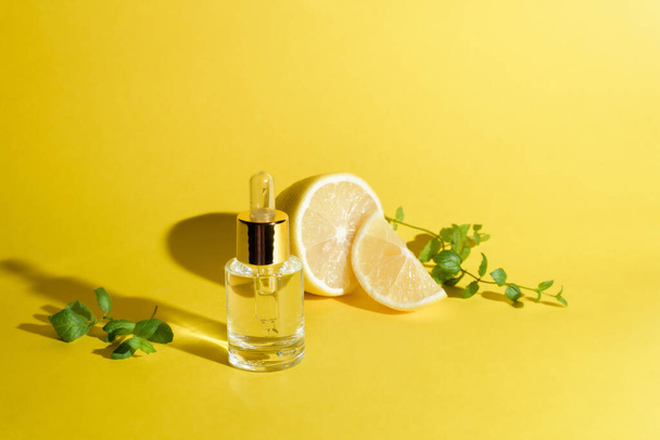 face serum with citrus fruit lemon and vitamin C in a glass bottle with a pipette on a yellow background, self-care concept skin care at home. - Foto, afbeelding