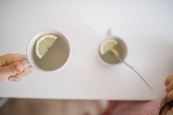 Mano tenendo una tazza di tè al limone con una fetta di limone all'interno - Foto, immagini