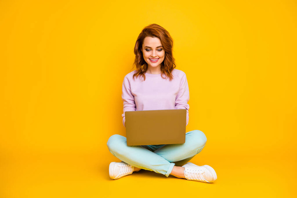 Full size photo of positive cheerful woman sit legs crossed use computer read news communicate online with colleagues family wear teal jumper isolated over yellow color background - Foto, Imagen