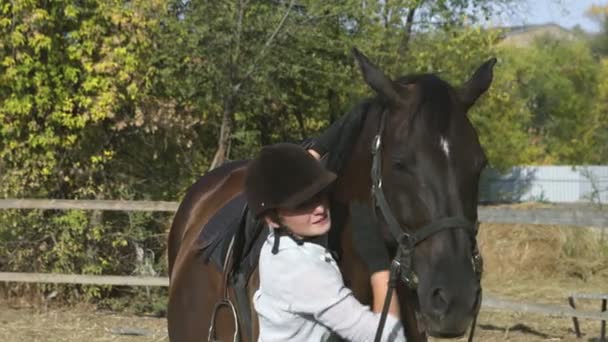 Γυναίκα αναβάτης σε ιππασία ρούχα και κράνος χαϊδεύοντας το άλογό της μετά τη βόλτα - Πλάνα, βίντεο
