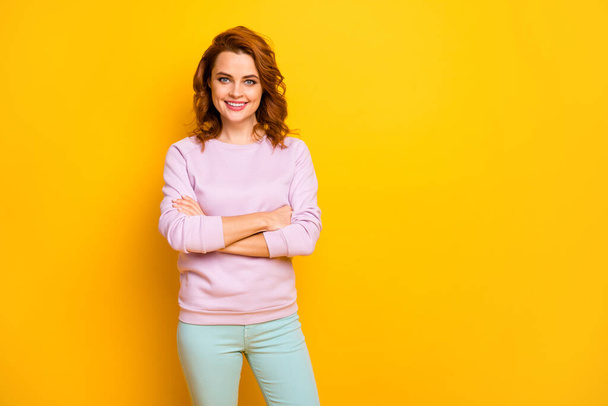 Photo of beautiful ginger curly lady hands crossed business company ceo boss friendly toothy smiling wear pink pullover green trousers isolated yellow color background - 写真・画像