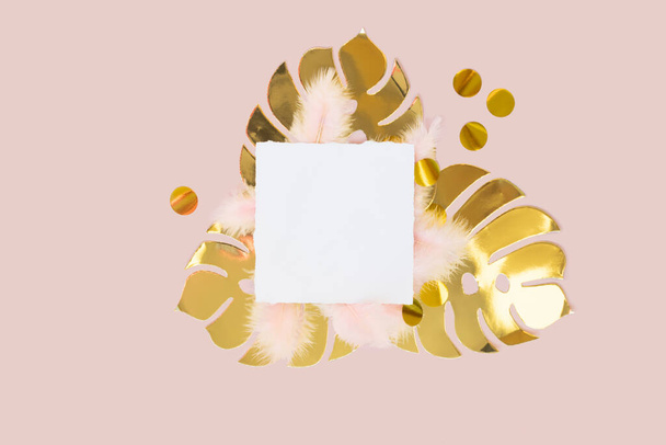 papier doré feuilles de monstère avec des plumes duveteuses roses et confettis ronds d'or sur un fond rose pastel - Photo, image