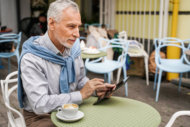 Cheerful senior man portrait - Mature adult using his computer laptop in a bar coffeehouse, concepts about lifestyle, senior people, technology and smart working - 写真・画像