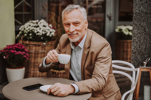 Cheerful senior man portrait. Mature adult sitting in a caf restaurant outdoors - Foto, Imagem