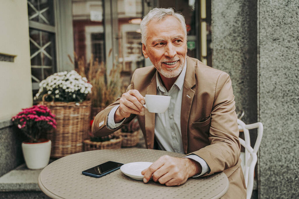 Cheerful senior man portrait. Mature adult sitting in a caf restaurant outdoors - Фото, зображення