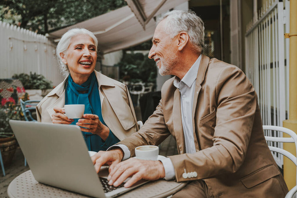 Beautiful senior couple dating outdoors - Mature couple with laptop computer sitting in a bar restaurant, concepts about elderly, lifestyle and technology - Foto, Bild