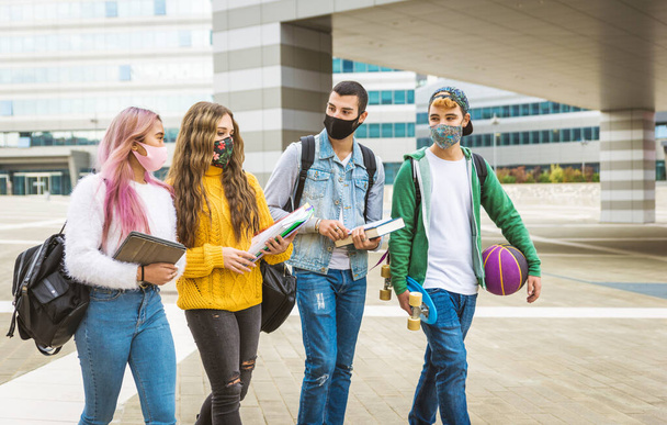 Happy young people meeting outdoors and wearing face masks during covid-19 pandemic - Group of cheerful teenagers having fun, concepts about teenage, lifestyle and generation z - Foto, Imagen