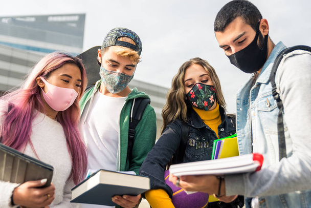 Happy young people meeting outdoors and wearing face masks during covid-19 pandemic - Group of cheerful teenagers having fun, concepts about teenage, lifestyle and generation z - Foto, Bild