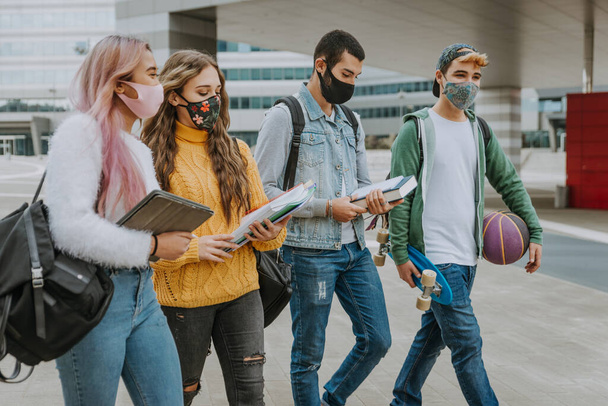 Happy young people meeting outdoors and wearing face masks during covid-19 pandemic - Group of cheerful teenagers having fun, concepts about teenage, lifestyle and generation z - Фото, зображення