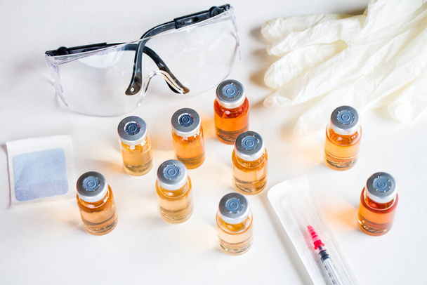 Vacina em ampolas e garrafas, agulha, luva e vidro de segurança. - Foto, Imagem